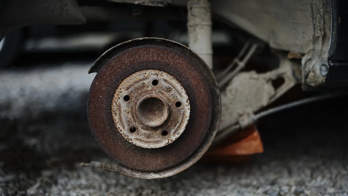 Rusty brake disc on a parked car with the wheel removed